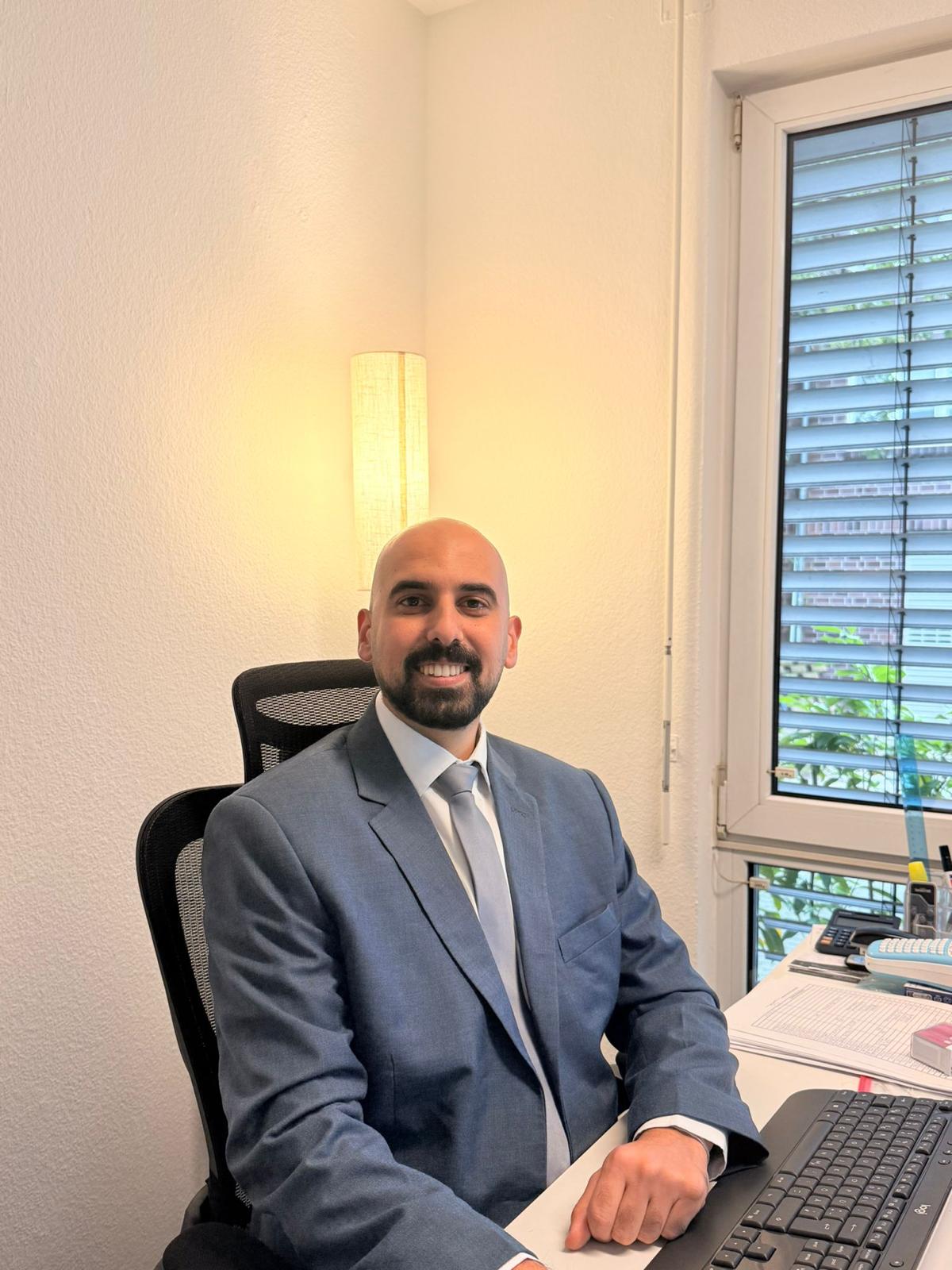 Mitarbeiter im Anzug mit Unterlagen am Arbeitsplatz